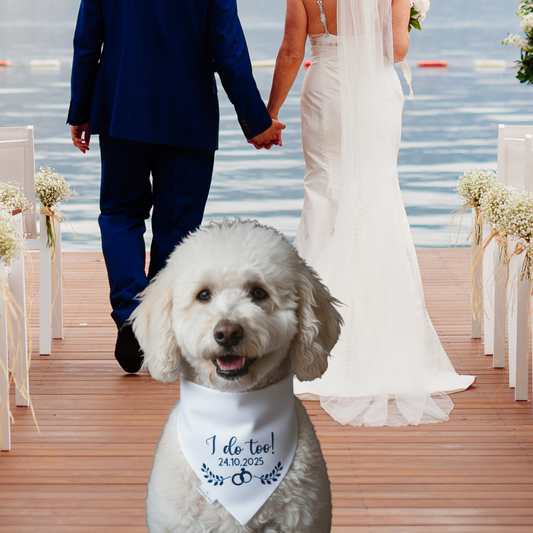 Dog wearing a 'I do too!' bandana at a wedding ceremony by a lake.
